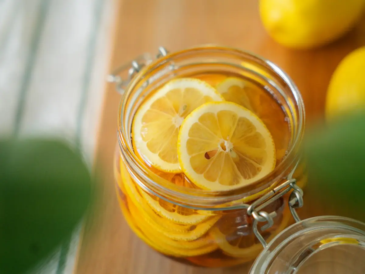 Irisan lemon terendam dalam toples kaca berisi cuka lemon